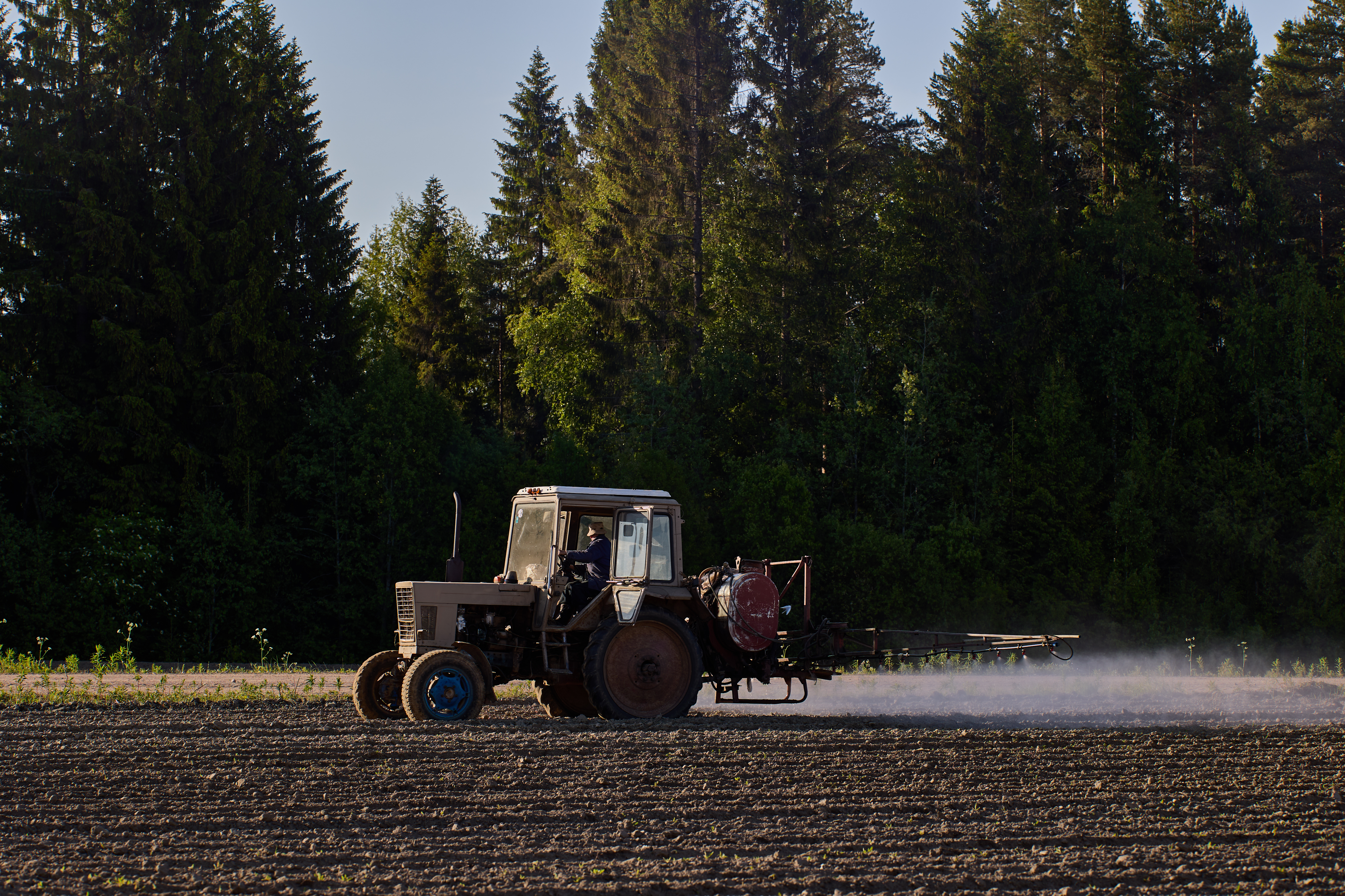 A tractor using a boom sprayer to apply herbicides to a potato field. | Source: Getty Images