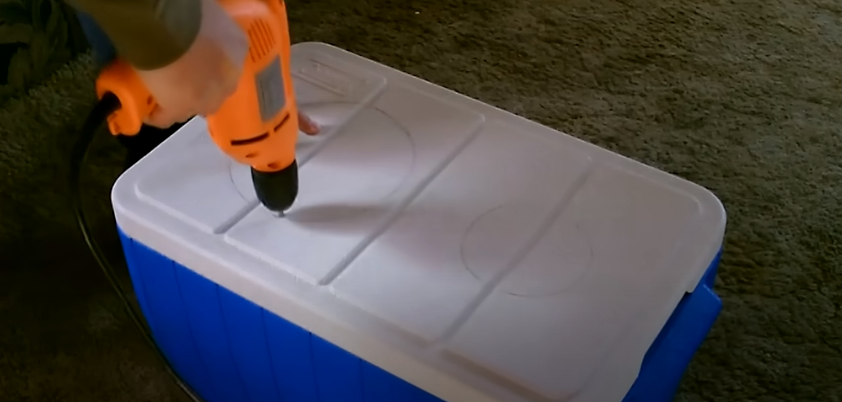A person drilling a hole on top of an icebox cooler | Source: YouTube/@desertsun02