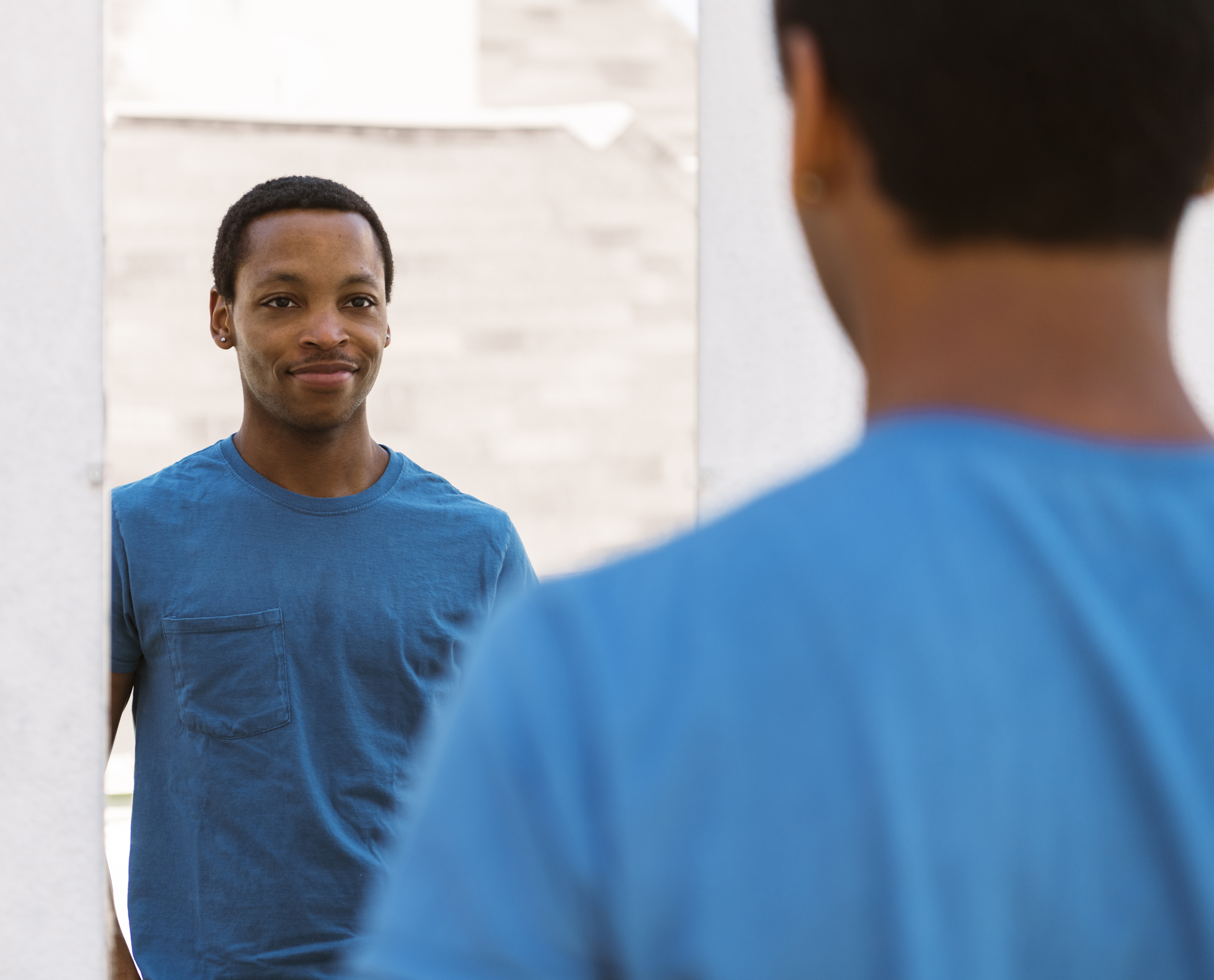 Smiling man looking at reflection in mirror