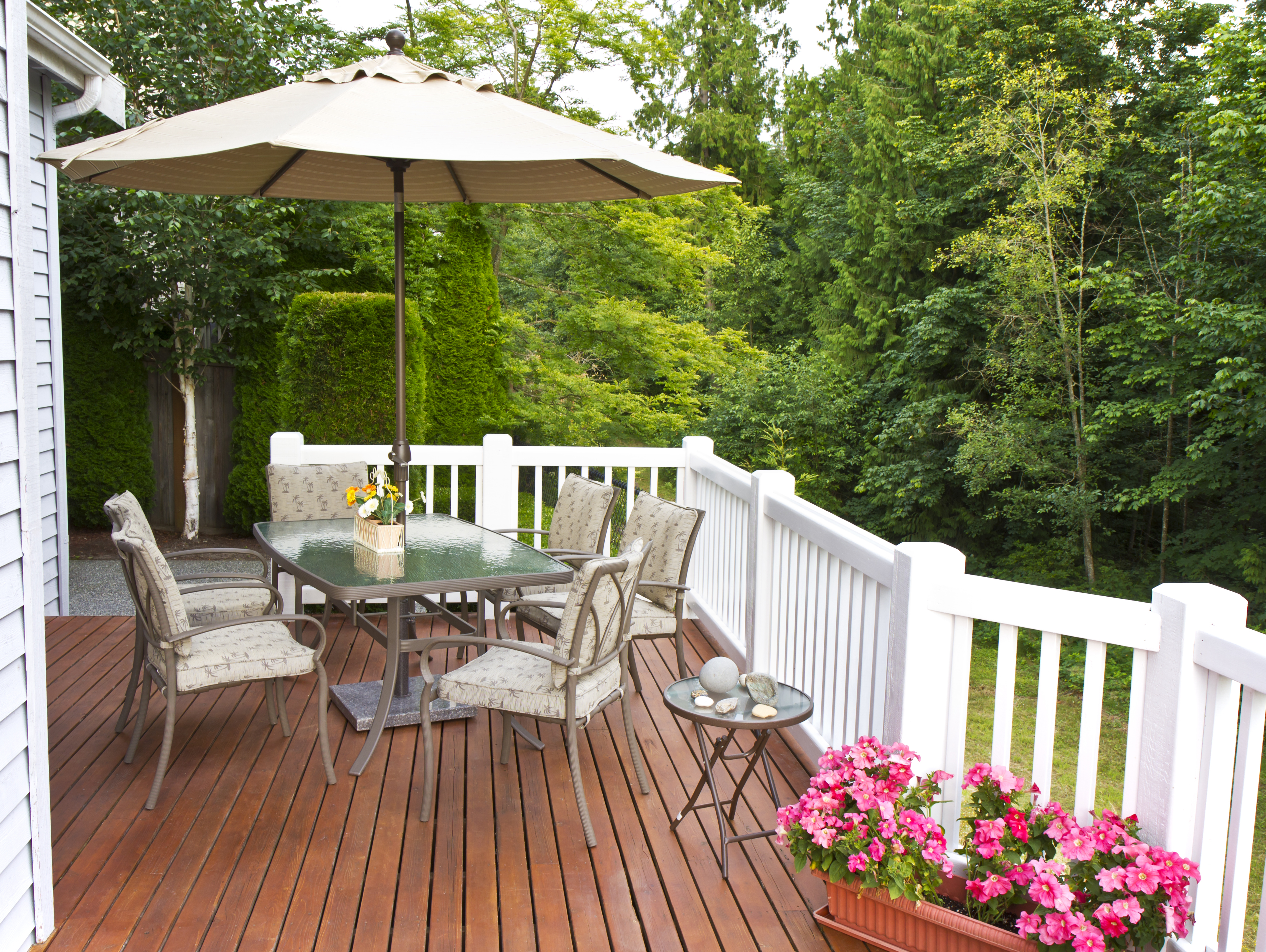 A patio on a wooden deck with trees in the background. | Source: Shutterstock