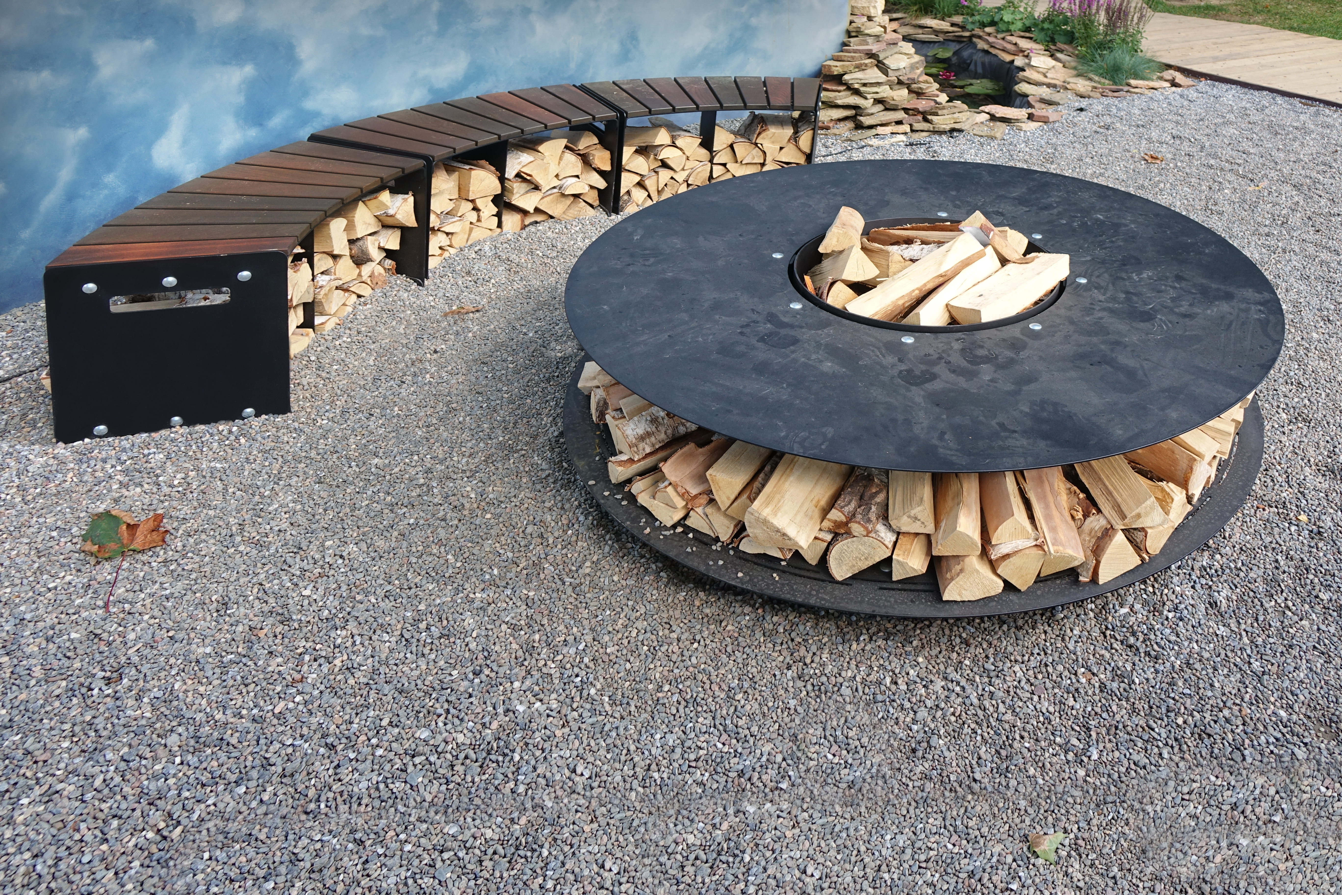 Pea gravel patio with a fire pit and log holder. | Source: Shutterstock