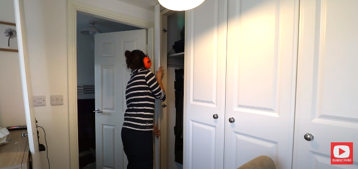 A woman sticking a trim piece on a wardrobe door frame | Source: YouTube/@TheCarpentersDaughterUK