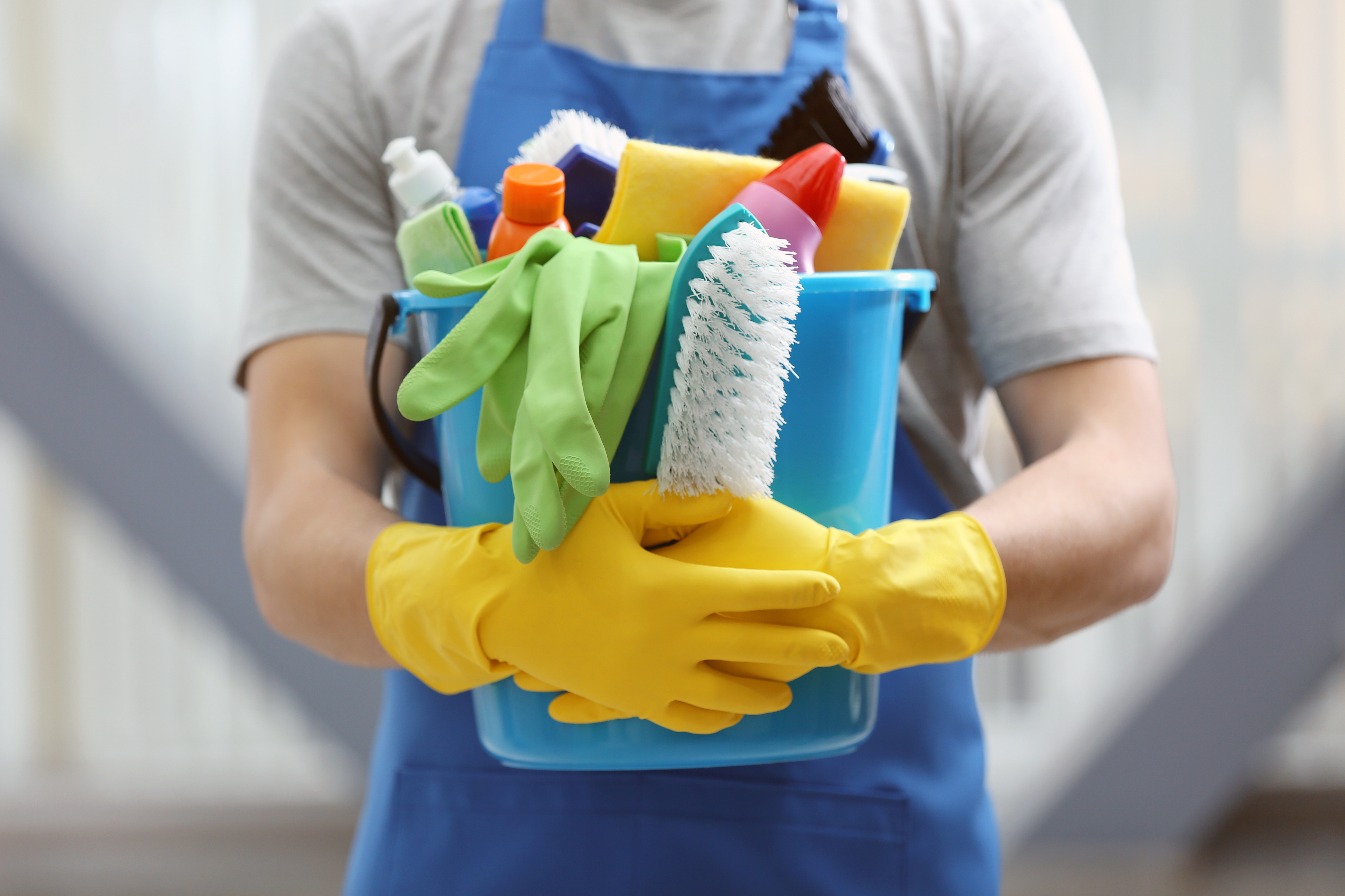 A young man carrying a bucket of cleaning supplies | Source: Shutterstock