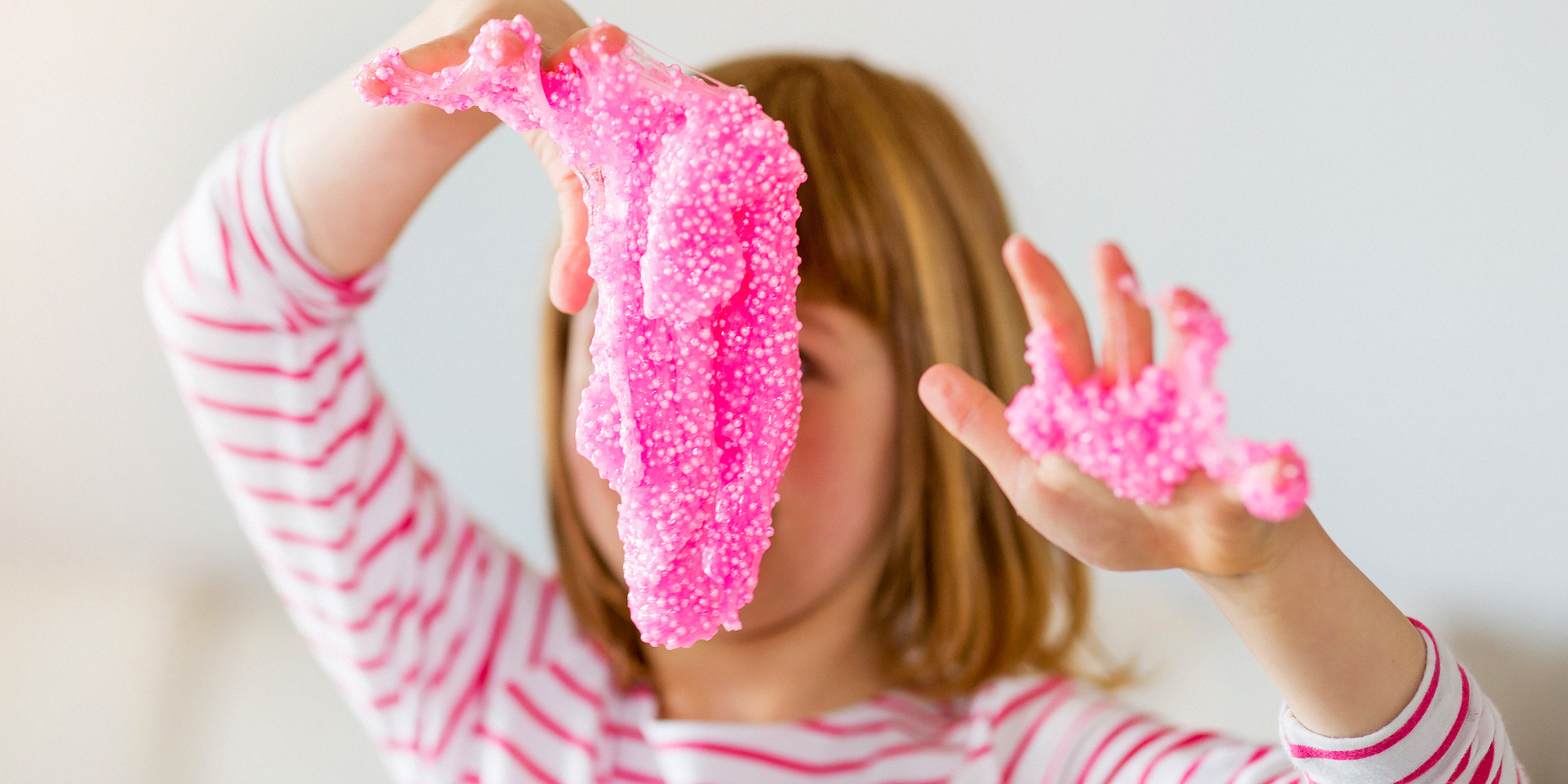 A little girl playing with pink slime | Source: Shutterstock