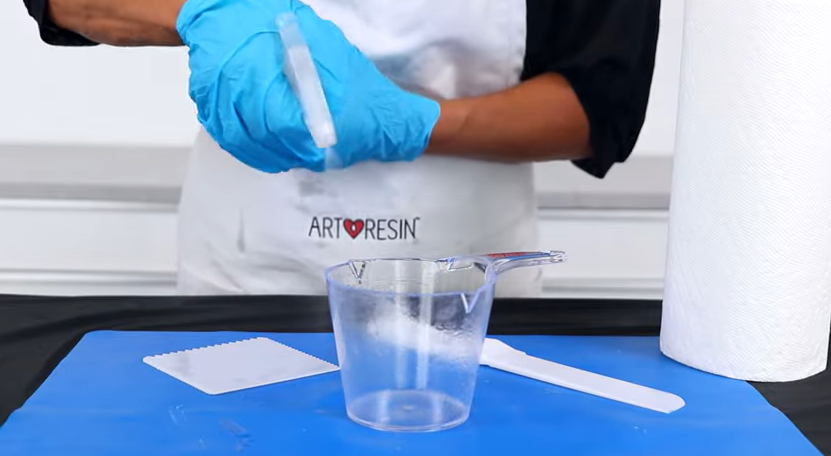 Sprits denatured alcohol or acetone into your mixing cup and wipe with a paper towel. | Source: YouTube/ArtResin