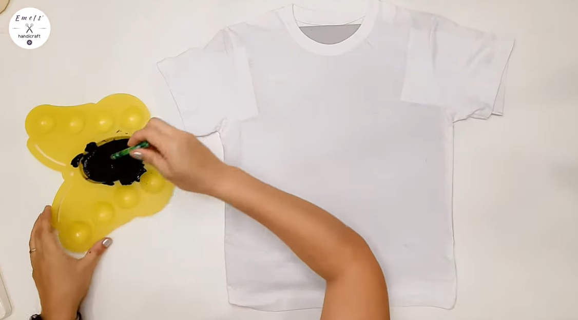The essential materials for crafting this DIY Dalmatian shirt include a white shirt and black paint. | Source: YouTube.com/emelshandicraft