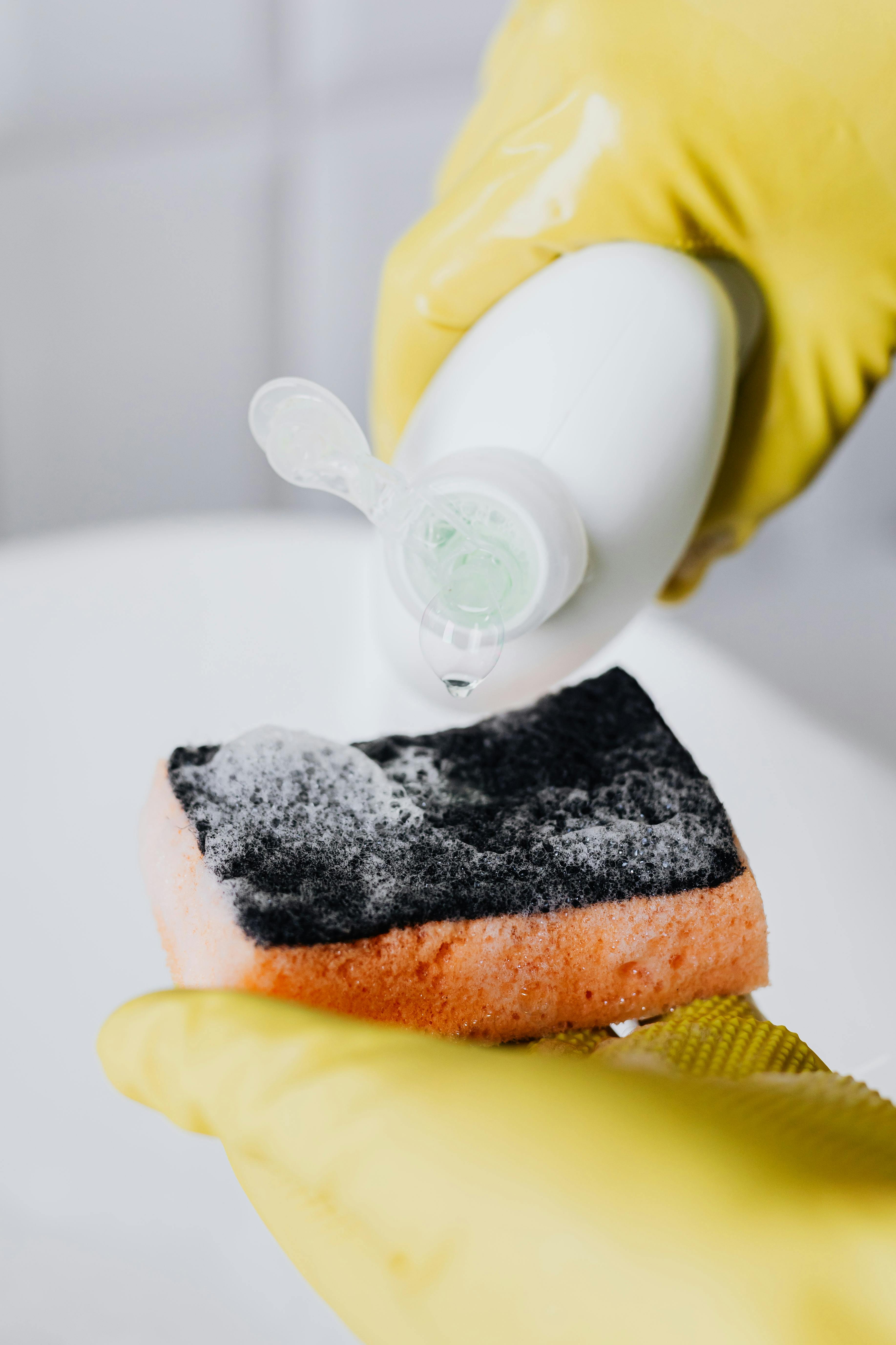 A person pouring dish soap onto a sponge | Source: Pexels