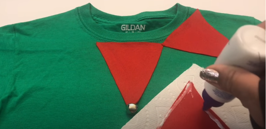 Use a glue to secure the pendants onto the T-shirt | Source: YouTube/@craftingwithgaby