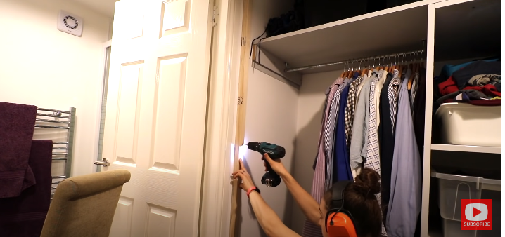 A woman drilling a hole to hang a wardrobe door | Source: YouTube/@TheCarpentersDaughterUK