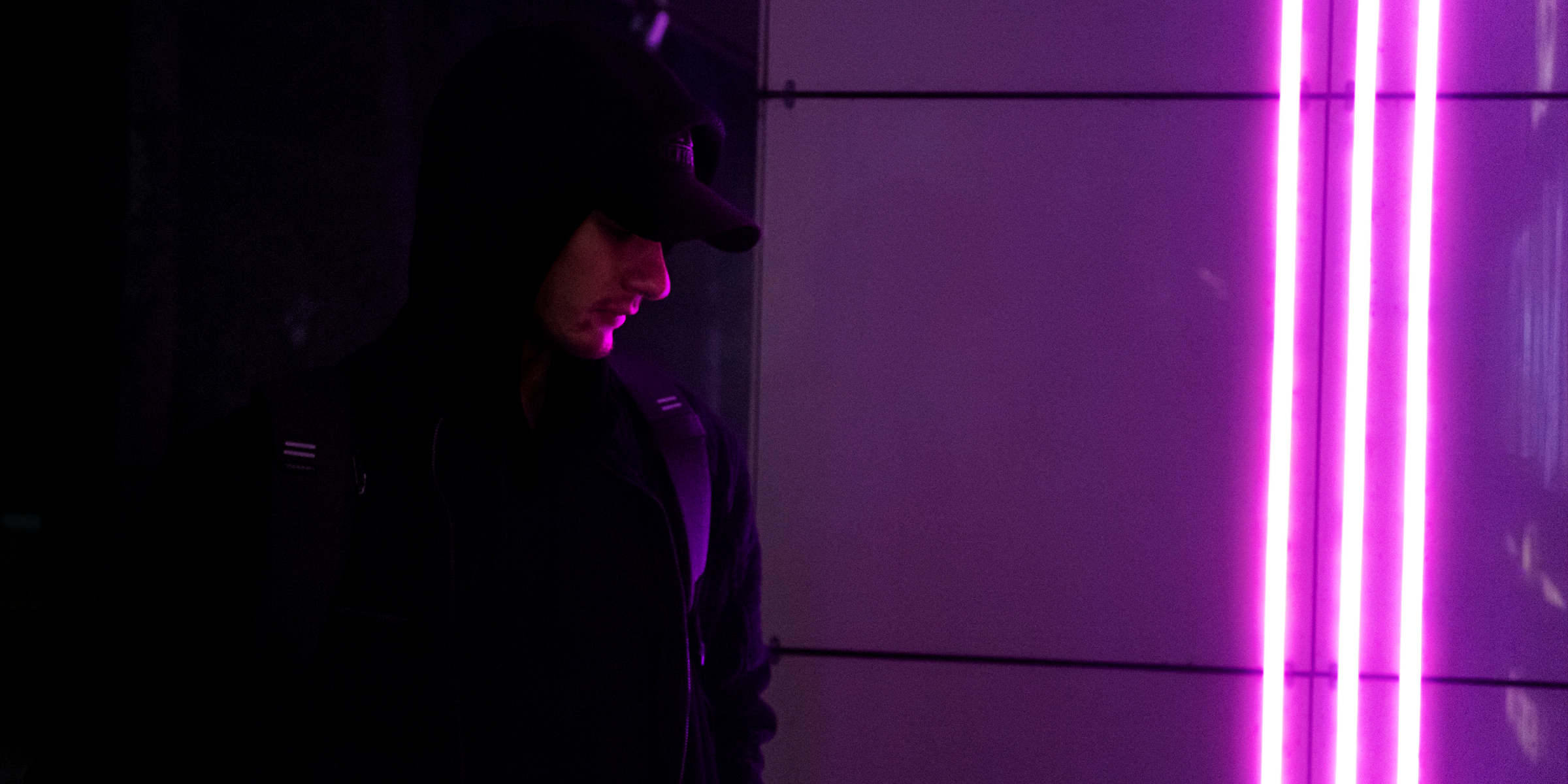 A man by a wall, looking at purple light | Source: Unsplash