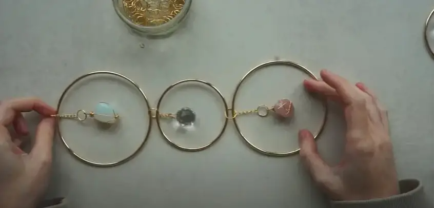 For the prism on the far left, repeat steps 4 and 5 but attach the loose end of the chain to another jump ring and connect that to the left-hand side of the hoop. | Source: YouTube/Vanir Creations