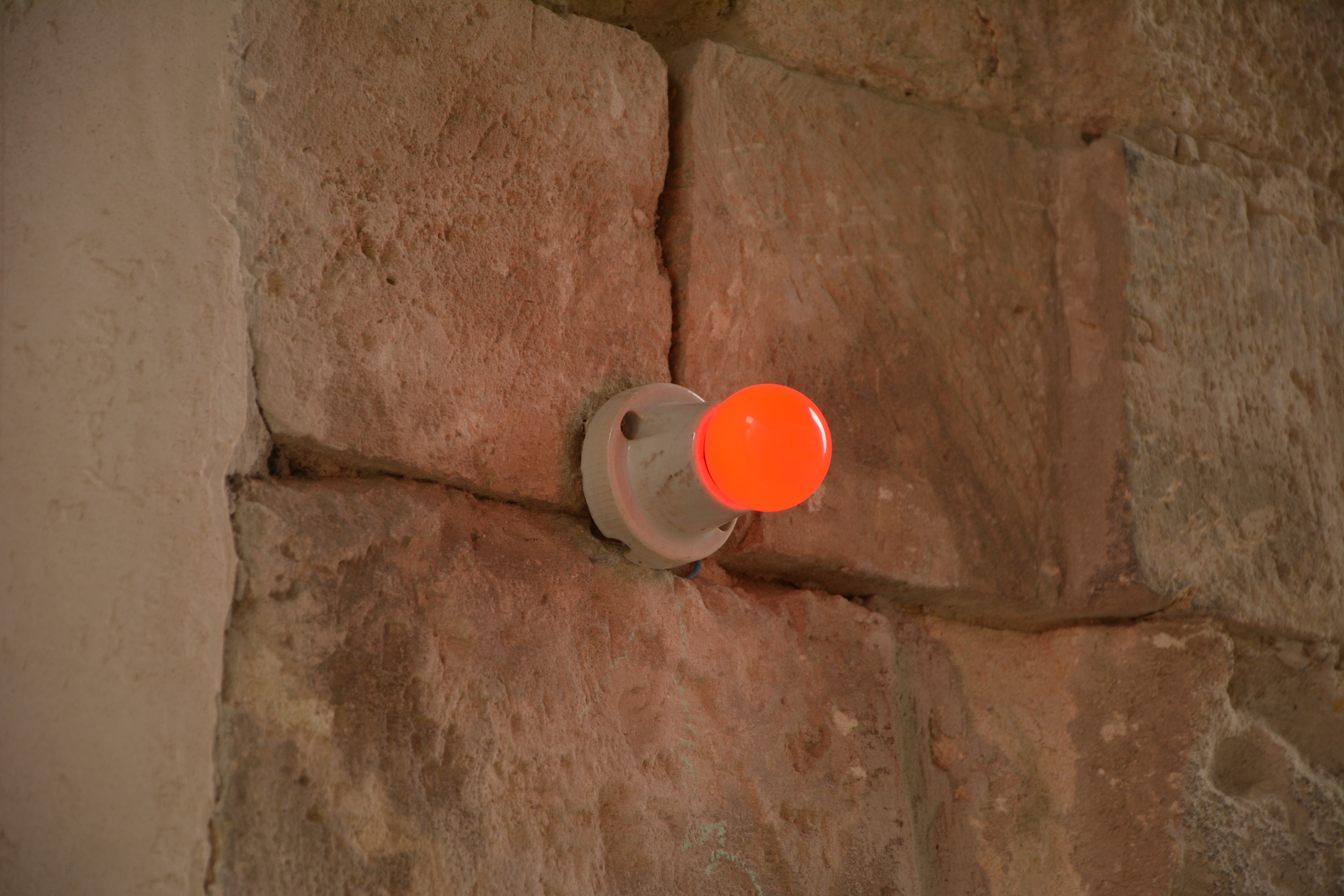 A red light bulb mounted on a stone wall | Source: Shutterstock