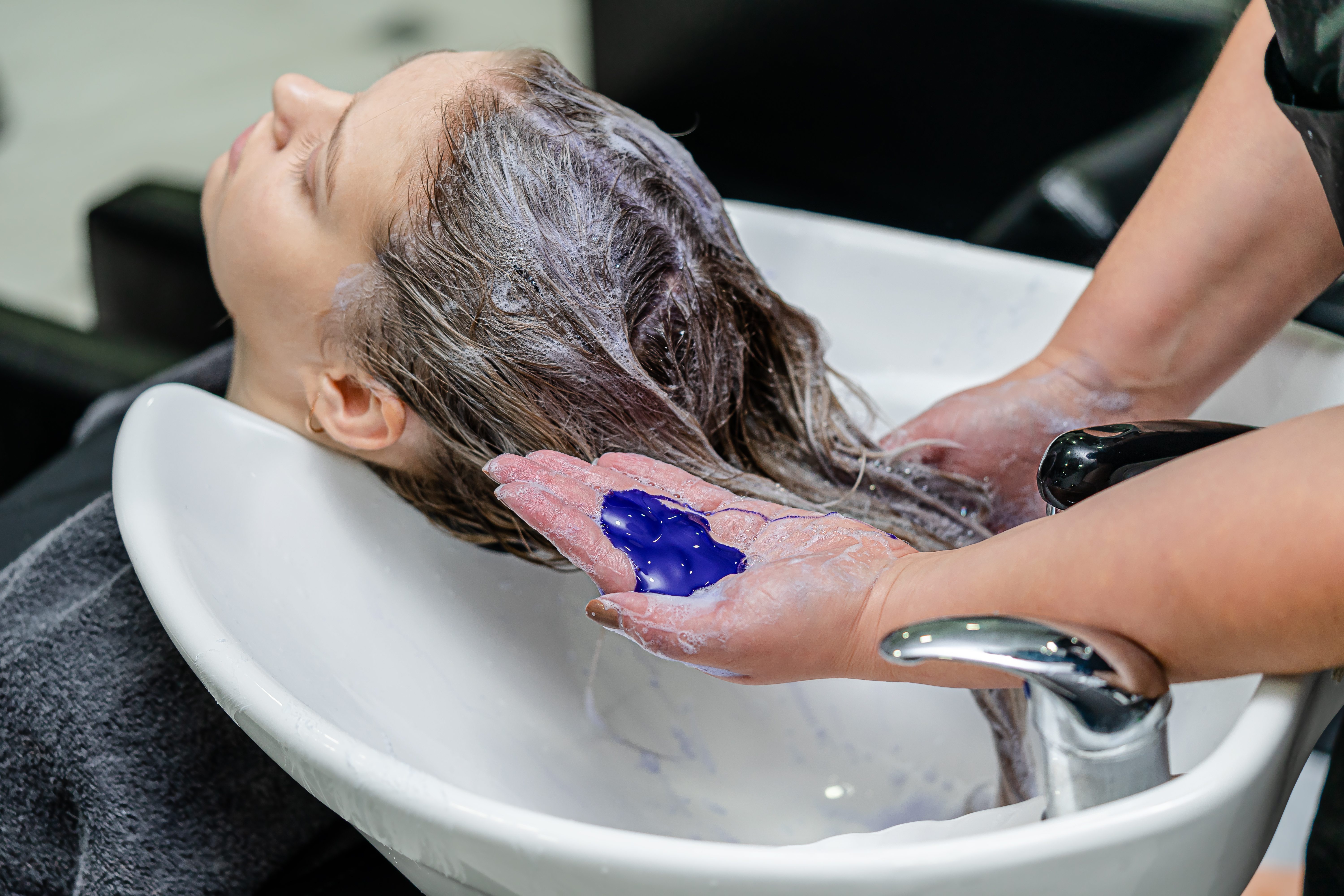 A woman getting her hair washed with purple shampoo | Source: Shutterstock
